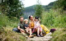 Family With Small Children Hiking Outdoors In Summer Nature, Sitting And Resting.