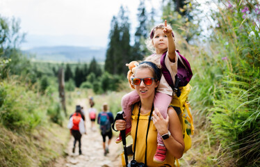 Wall Mural - mother with small toddler daughter hiking outdoors in summer nature, looking at camera.