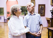 © caftor - mature European couple examines paintings in an exhibition in hall of art museum