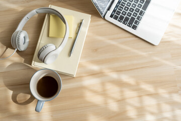 Wall Mural - top view of headphones coffee and laptop on floor home in morning and sunlight. flat lay