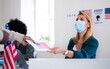 © Halfpoint - People with face mask voting in polling place, usa elections and coronavirus.