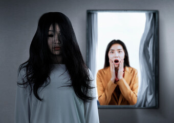 Asian businesswoman scared looking at a scary ghost woman in the abandoned house