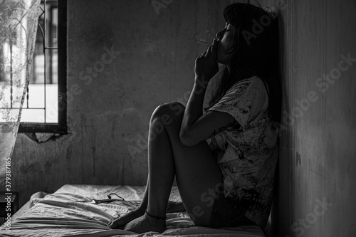 Fotomural A young Asian woman sitting in a cigarette smoking, unconscious