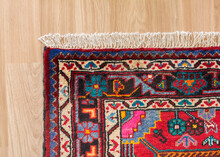 Edge Of A Persian Handmade Carpet On Laminate Flooring, Woven In Hamedan, Iran