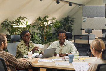 Wall Mural - portrait of two young african-american people smiling at colleagues while sitting at table during me