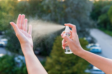 Women using an alcohol hand sanitizer from a spray bottle for cleaning hands and palms protection from viruses, Covid-19 and coronavirus	