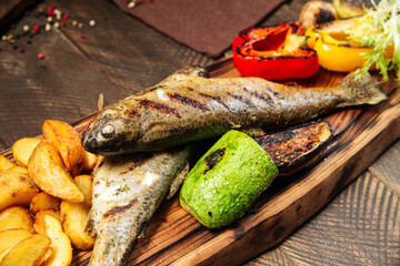 Wall Mural - Grilled fish with vegetables on the wooden board