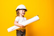 © dianagrytsku - Cute little girl engineer with helmet holding bluepring on yellow background