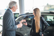 © Minerva Studio - Woman taking the keys for her car in a showroom