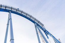 Part Of A Blue Rollercoaster  In Amusement Park Over Cloudy Sky