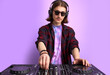 © Roman - caucasian stylish dj man in sunglasses mixing console on purple studio background, perform dance club music. portrait