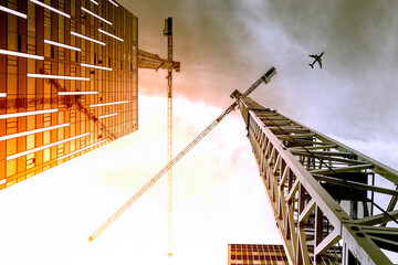 Tower crane. Bottom view of a tall construction cranes next to a modern building. Engineering and architecture design background