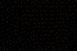 Many small glowing orange lights from a garland on a black background. Burning light bulbs in the dark