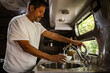 © Maskot - Smiling man filling drinking water through faucet in camper trailer