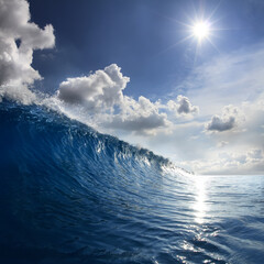 Fototapete - Blue Ocean Wave moving to a shore. Bright Day with sun and white puffy clouds on the sky
