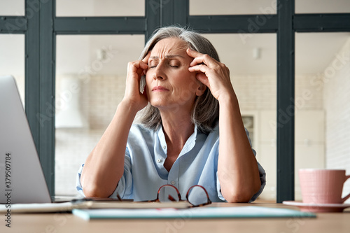 Fotografía Tired stressed old mature business woman suffering from headache at work