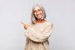 © kues1 - gray haired woman looking excited and surprised pointing to the side and upwards to copy space