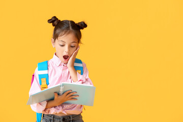 Canvas Print - surprised little schoolgirl with notebook on color background