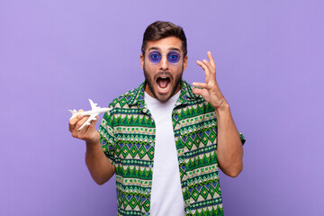 young man screaming with hands up in the air, feeling furious, frustrated, stressed and upset. holidays concept