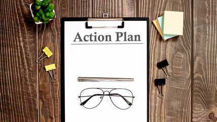 Poster - ACTION PLAN text form on a wooden table.
