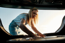Attractive Young Woman Taking Out Spare Wheel To Change On The Broken Car On Her Own
