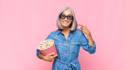 Wall Mural - middle age woman smiling confidently pointing to own broad smile, positive, relaxed, satisfied attitude movie concept