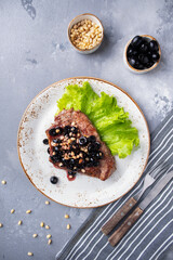 Canvas Print - Top view of roast meat with black olives, nuts and red sauce served with fork and knife. Reastaurant food.