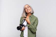 Middle Age Woman Smiling Cheerfully, Feeling Happy And Pointing To The Side And Upwards, Showing Object In Copy Space. Photographer Concept