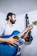 © JAVIER LARRAONDO - Portrait of young man playing on acoustic guitar at studio.Focus selective.Music and professional musicians concept.Save the culture