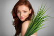 © Prostock-studio - Red-Haired Young Lady Posing With Green Leaves Over Gray Background