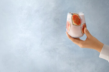 Wall Mural - Woman holding fig smoothie on light blue background, closeup. Space for text