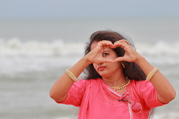 A South Indian female model posing on the Marina coast of Chennai with the help of fingers of both hands composing the heart