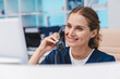 © InsideCreativeHouse - Young female doctor practitioner working at reception desk while answering phone calls and scheduling appointments