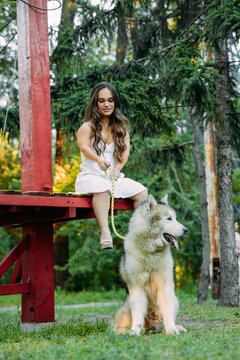 Young dwarf woman sits on bench near dog in park.