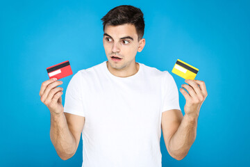 Canvas Print - Young man holding credit cards on blue background