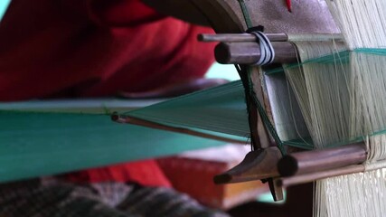 Wall Mural - Slow motion woman working on weaving machine for weave handmade fabric. Textile weaving. Weaving using traditional hand weaving loom on cotton strands. Textile or cloth production. Asian culture.