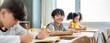 © paulaphoto - Portrait of little pupil writing at desk in classroom at the elementary school. Student boyl doing test in primary school. Children writing notes in classroom. Education knowledge banner