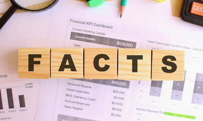 Wooden cubes with letters on the table in the office. Text FACTS. Financial concept.