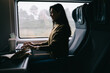 © BullRun - Cheerful Asian woman messaging on laptop in bus