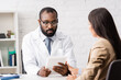 © LIGHTFIELD STUDIOS - selective focus of brunette woman near serious african american doctor in eyeglasses using digital tablet
