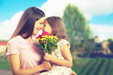 Wall Mural - Mother and daughter with bouquet of flowers on blurred background.