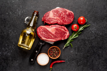 Two raw marbled beef steak a on a meat knife on a stone background

