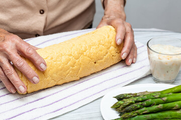 Wall Mural - Close up of a senior woman hands rolling a just baked sponge cake