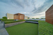 © tampatra - Sky garden on private rooftop of condominium or hotel, high rise architecture building with tree, grass field, and blue sky.