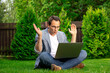 © Model Republic - Joyful surprised middle aged businessman sits on grass works outdoors, looks with surprise at laptop screen, man happy with stock growth and higher earnings profit, winner, success concept, copy space