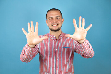 Russian business man wearing a red shirt over blue background showing and pointing up with fingers number ten while smiling confident and happy.