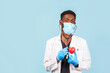 © Nana_studio - african american male doctor with stethoscope in mask holding red heart on blue background. cardiologist
