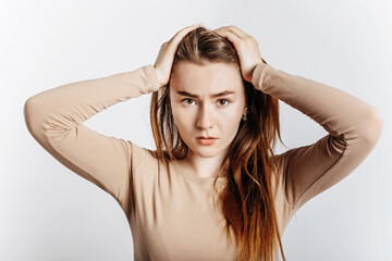 Wall Mural - Beautiful young brunette girl in horror holding her head on an isolated white background. The woman is shocked by the bad news. Advertising space