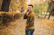 © anatoliycherkas - Portrait of handsome and happy guy smiling and talking on the phone in the autumn park