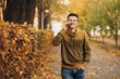 © anatoliycherkas - Portrait of handsome and happy guy smiling and talking on the phone in the autumn park